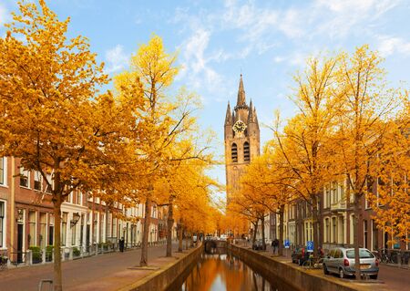 Street with canal and Old Church falling tower of Delft, Holland at fallの写真素材