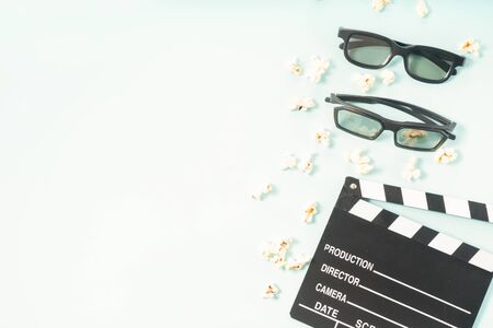 popcorn, cinema clapper and two pairs of 3d glasses over blue background, movie and cinema concept