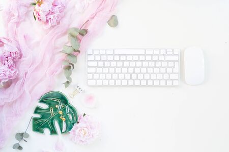 Flat lay home office workspace - modern keyboard with female accessories and fresh peony flowersの写真素材