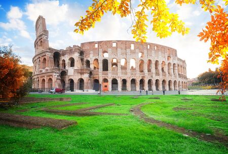 Ruins of antique Colosseum with grass lawn in sunrise lights, Rome Italy at fall dayの写真素材