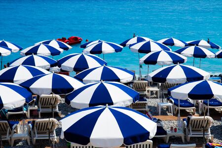 Turquoise water of cote dAzur over blue and white beach umbrellas, Franceの写真素材