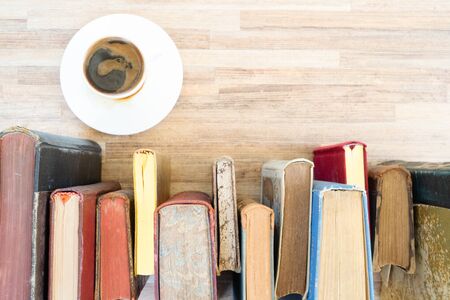Books row on wooden table with white cup of coffee, top view flat lay. Reading, learning, literature conceptの写真素材