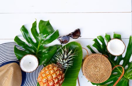 Summer flat lay scenery boder with hat, bag, leaves and fruits on white wooden backgroundの写真素材