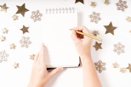 Wish list for Cristmas and New Year. Holiday decorations and ruled notebook with wish list and somwones hands, flat lay top viewの写真素材