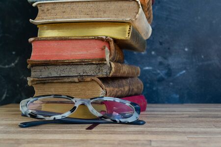 Stack of multicolored books, education, reading, back to school concept, glasses on the tableの写真素材