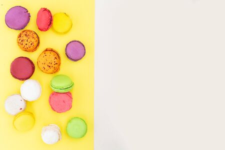 Border of fresh fresh macaroon biscuit, top view over yellow and beige backgroundの写真素材