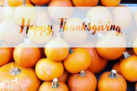 orange raw pumpkins pile on old wooden textured table, top view with happy thanksgiving greetingsの写真素材