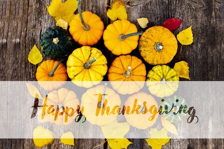 orange and green raw pumpkins on old wooden textured table, top view with happy thanksgiving greetingsの写真素材