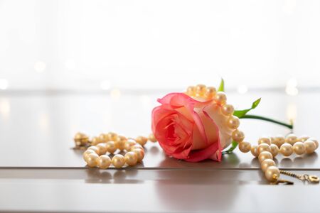 Rose fresh flower and jewellery on gray table by the windowの写真素材