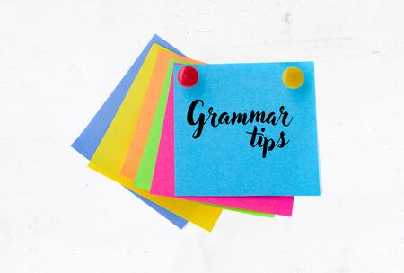 grammat tips on eticky paper notes over white wooden background