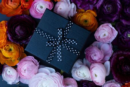Fresh flowers with gift box, close up on black background