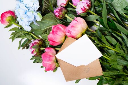 Beautiful fresh pink peony and hydrangea flowers on white table close up, top view and flat lay background with copy space on white cardの写真素材