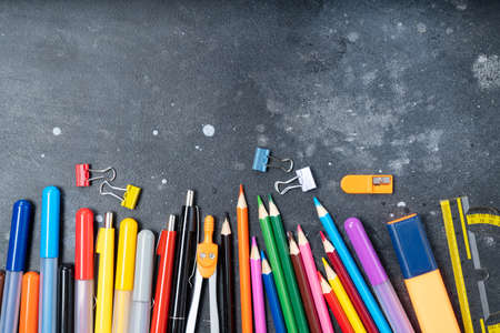 Back to school concept, border with colorful school supplies on blackboard background with copy...