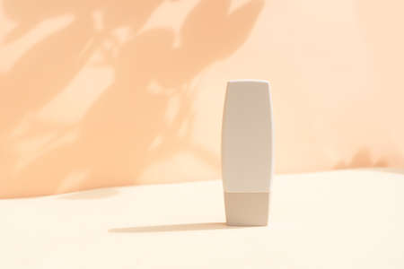Minimal modern cosmetic product display on textured beige background with shadow overlayの写真素材