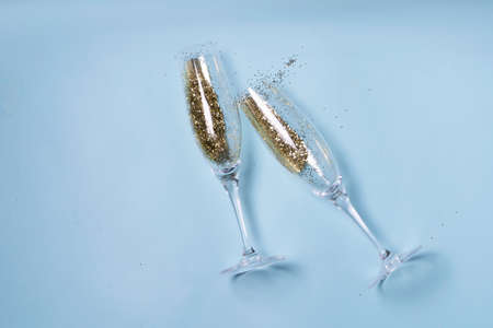 Two glasses with Christmas and Happy New Year Champagne over blue backgroundの写真素材