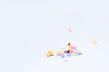 Pile of colorful medical pills falling on blue background. Medical pharmacy concept. Antibiotic drug...