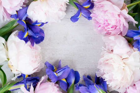 Fresh peony and iris flowersframe, copy space on white desk