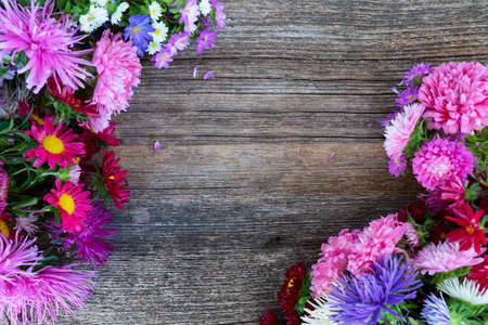aster fresh flowers, top view frame on aged wooden background, naturall fall flowers background