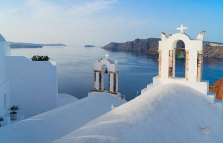 two white church belfries and volcano caldera with sea landscape, beautiful details of Santorini island, Greeceの写真素材