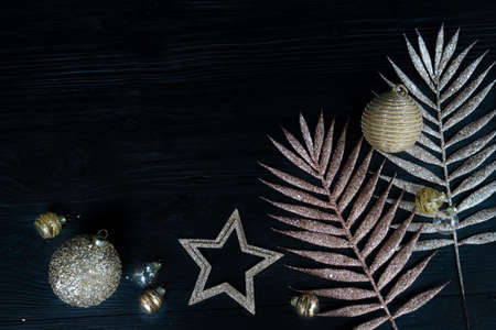 Golden tropical palm leaves with christmas decorations on black background with copy space, top view borderの写真素材