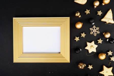Golden christmas decorations with gingerbread cookies over black background, copy space on frame