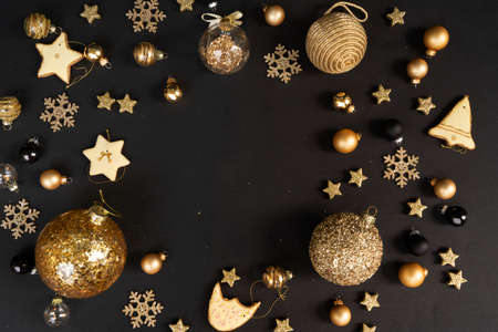 Golden christmas decorations with gingerbread cookies over black background, frame with copy spaceの写真素材