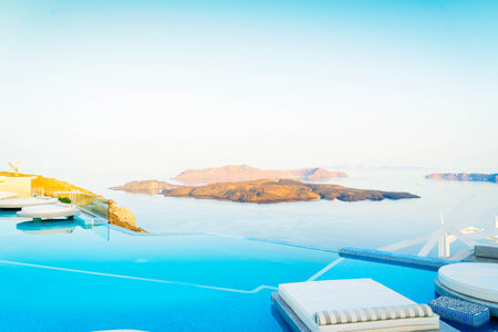 clear blue pool water with chair beds and view of Santorini caldera, Greece, tonedの写真素材