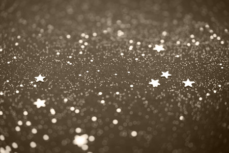 Beautiful Christmas light background. Abstract glitter bokeh and scattered sparkles in gold, on black, tonedの写真素材