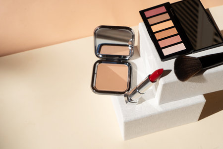 Minimal modern cosmetic scene with make up brushes, eye shadows palette, lipstick, powder, neutral beige colors with copy spaceの写真素材