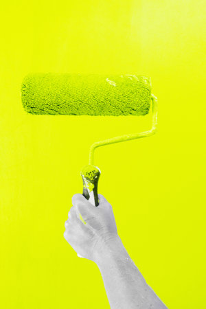 Someone painting white wall in illuminating yellow color, hand holding paint rollerの写真素材