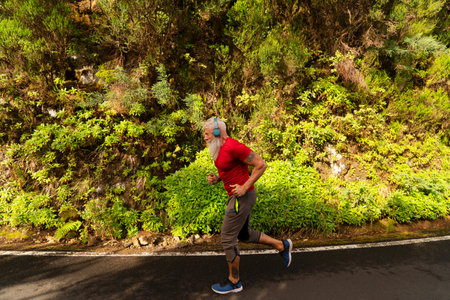 Senior man with white beard doing running outdoor on the natureの写真素材