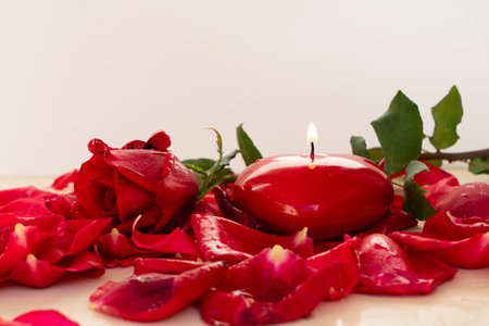 Key with the burning candle heart as a symbol of love with rose petals over neutral beige backgroundの写真素材