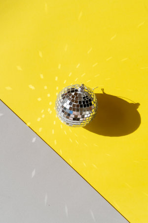One disco balls on ulitimate gray and illuminating yellow backgroundの写真素材