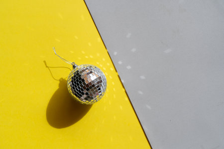 One disco balls on ulitimate gray and illuminating yellow backgroundの写真素材