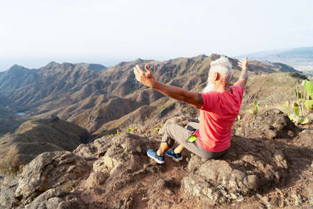 Senior athlete man greeting sunrise, mindful living and healthy wellbeing conceptの写真素材