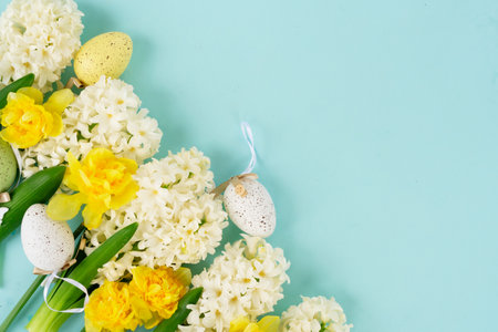 hyacinth and daffodils flowers with easter eggs border over blue background close up