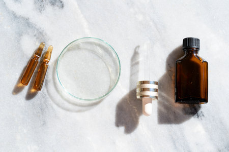 Glass petri dish with transparent pure serum for skin care on marble white background, top view. Concept laboratory tests and research, making natural organic cosmeticの写真素材