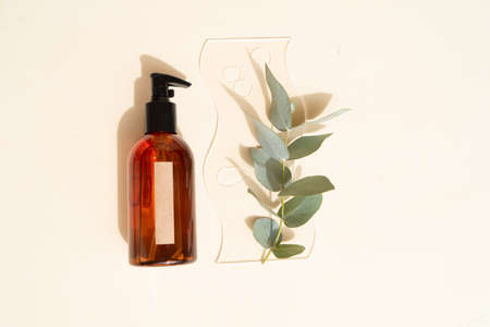 Natural cosmetics bottle with eucaliptus on earth tones brown background