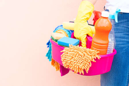 caucasian woman holding basin with cleaning supplies