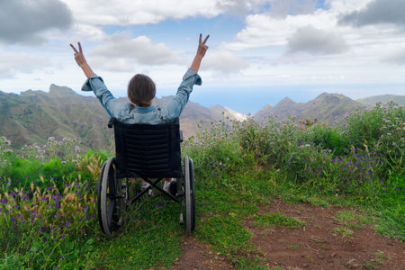 Disabled handicapped woman in wheelchair on mountain hill enjoying view