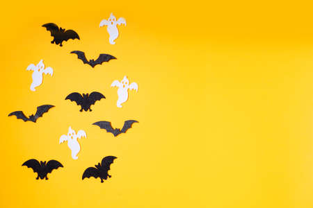 Halloween flat lay top view scene with bats and ghosts on orange background with copy space
