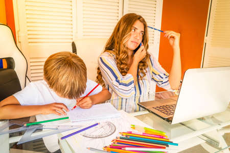 tired mother mother sititng at the desk with son at her lap, peaceful mom using modern computer, work from home at quarantine time, virus pandemia lifestyle, parenting, upbringingの写真素材
