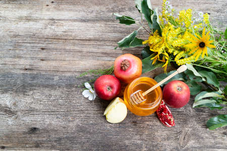 rosh hashana holiday - honey jar with apples and pomergranates on rustic background, top view with copy spaceの写真素材