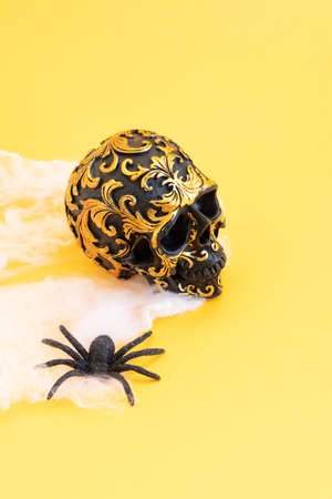 Dia de los muertos traditional holiday - day of the dead - skull in flowers, traditional symbol over yellow background with spiderの写真素材