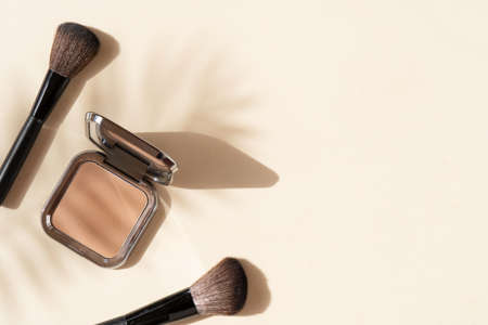 Minimal modern cosmetic scene with make up brushes, powder and shadow overlayの写真素材