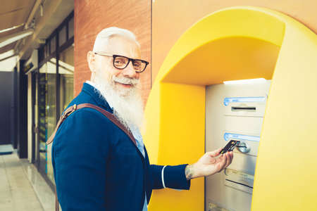 Senior man with ATM, Happy mature male using bank cash machine - Concept of business, banking account and lifestyle peopleの写真素材