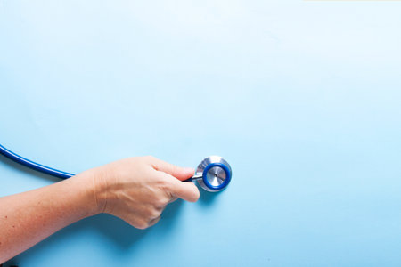 Healthcare concept - someones hand holding stethoscopee on blue backgroundの写真素材