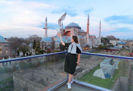 tourist girl feeding seaguls in front of hagia sophia cathedral church, Istanbul Turkey