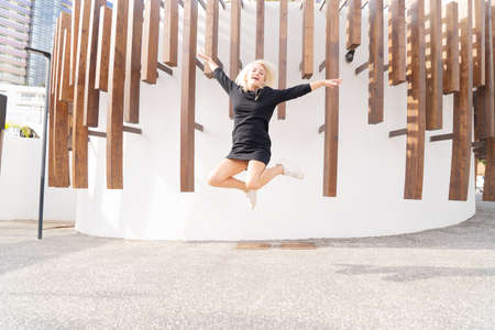 happy caucasian woman jumping, generic city in background, happy people lifestyleの写真素材