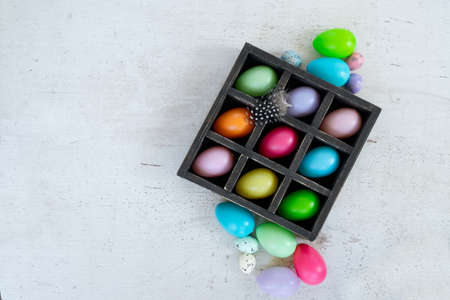 Easter scene with colored eggs over wooden table background, copy space